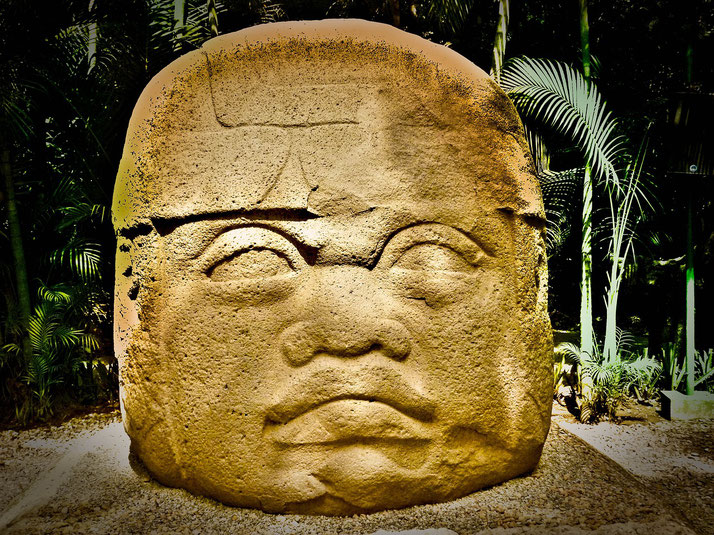 A large Olmec stone head sculpture with a helmet-like headdress, carved from basalt.