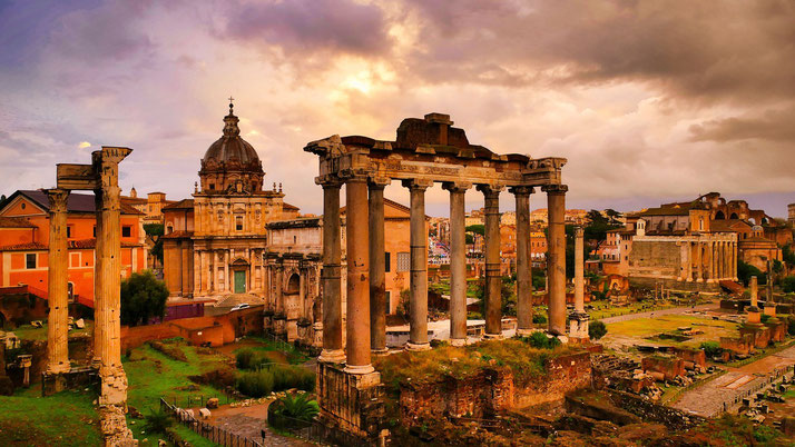 The Roman Forum at sunset, with the ruins of the Temple of Saturn in the foreground.