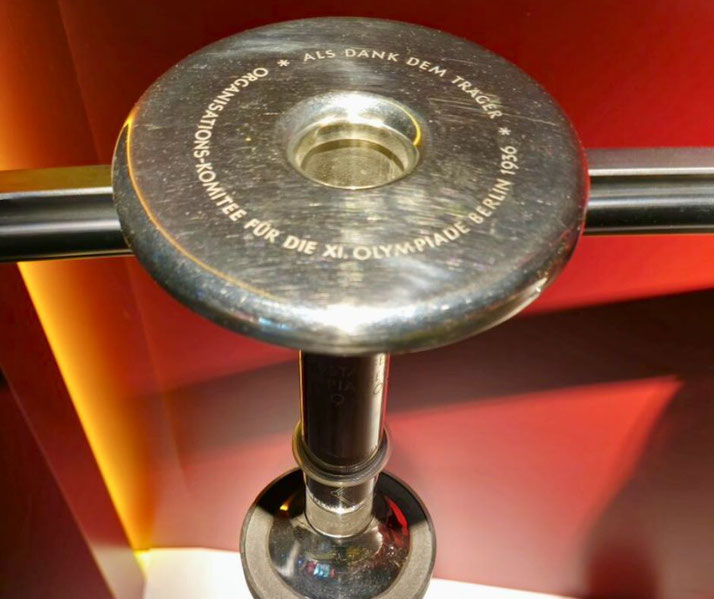 An Olympic torch from the 1936 Berlin Games. The metal surface bears an inscription honoring the torchbearers, commemorating the XI Olympiad, a pivotal moment in Olympic history.