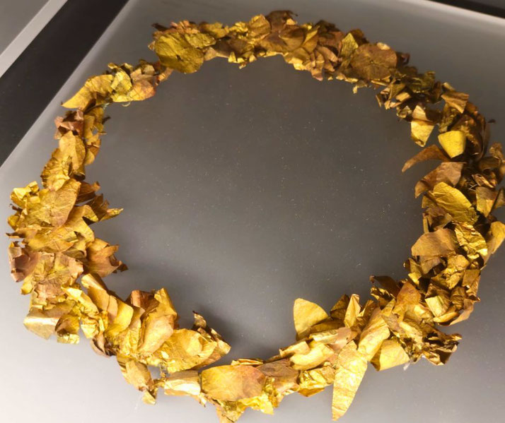 Ancient golden wreath made of intricately shaped gold leaves, arranged in a circular form resembling a laurel crown.