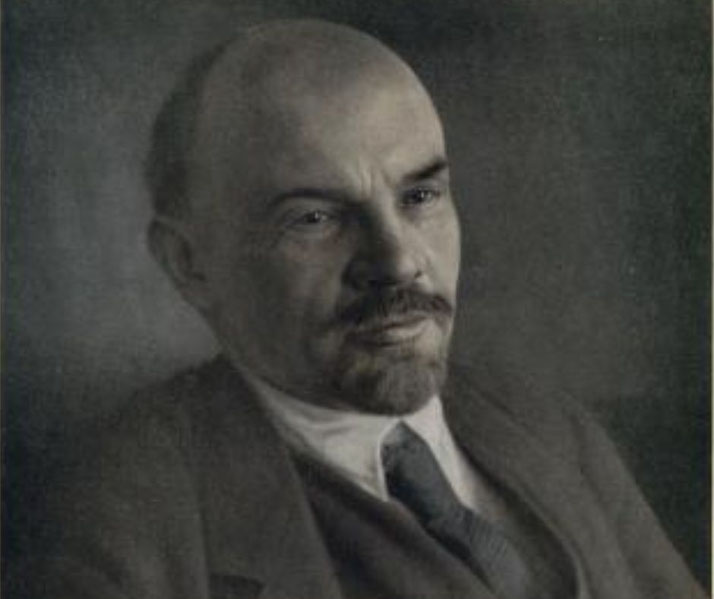 A bald man with a goatee in a suit and tie looks slightly off-camera in a serious vintage portrait.