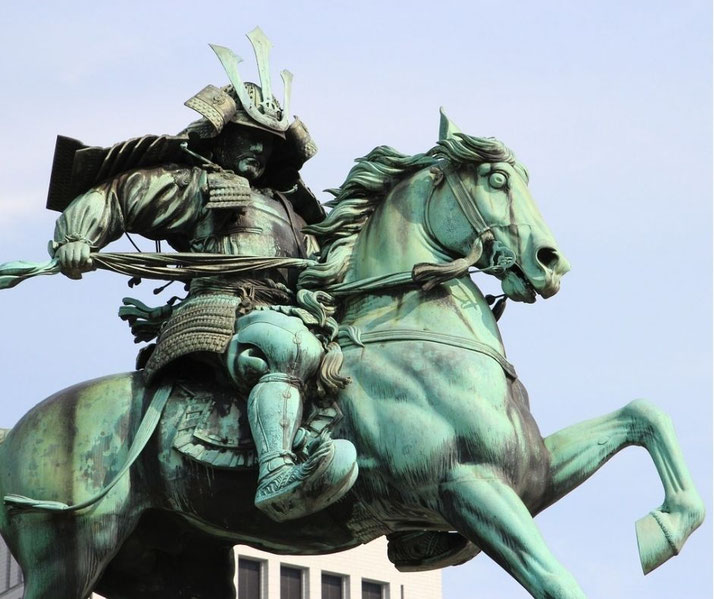 A bronze equestrian statue of a samurai warrior in full armor, wielding a bow. The dynamic pose and intricate details capture the power and tradition of Japan’s feudal era.
