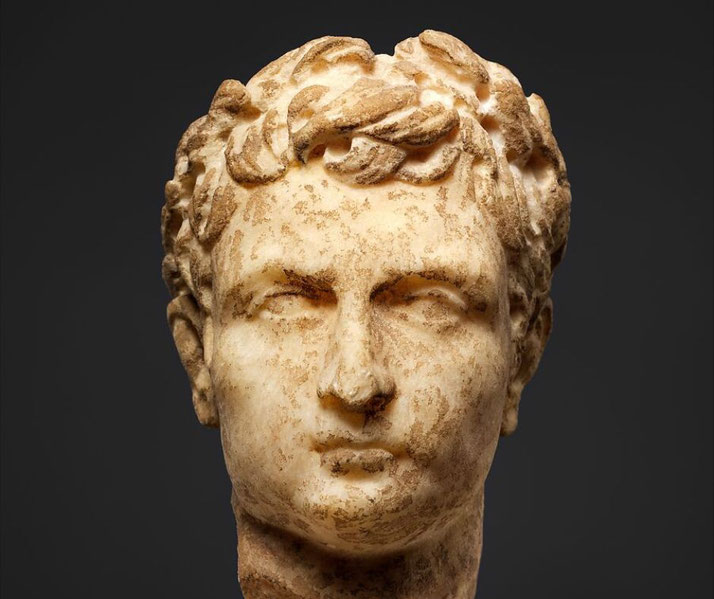Small Roman marble head, possibly depicting Emperor Augustus, adorned with a laurel wreath.