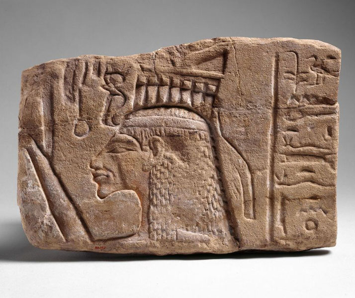 Sandstone relief showing Queen Nefertiti with raised arm offering to Aten, adorned with elaborate crown and Aten rays.