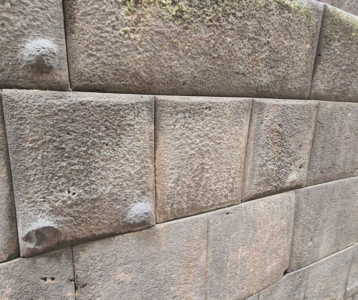 A section of an ancient Incan stone wall, featuring precisely cut and fitted stones.
