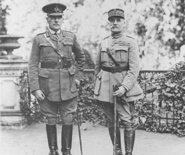 Two high-ranking military officers in formal uniforms stand side by side outdoors, both holding canes, with foliage and a decorative railing behind them.
