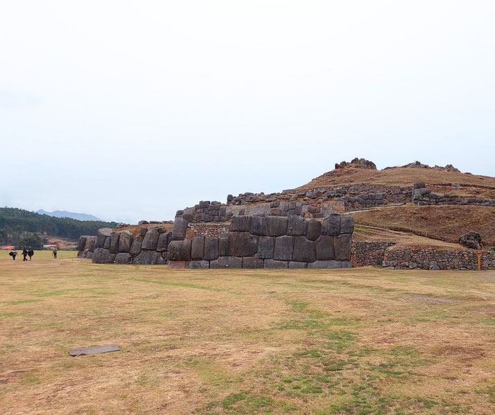 A wide view of Sacsayhuamán, an ancient Inca fortress in Peru, showcases its massive stone walls and terraced landscape. 