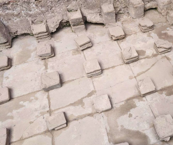 The remains of an ancient Roman underfloor heating system (hypocaust) at Pompeii. Stacked tiles once supported a raised floor, allowing warm air to circulate and heat the room above.