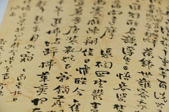 A close-up of traditional East Asian calligraphy on aged parchment, featuring elegant black ink characters arranged vertically, evoking a sense of historical and cultural significance.