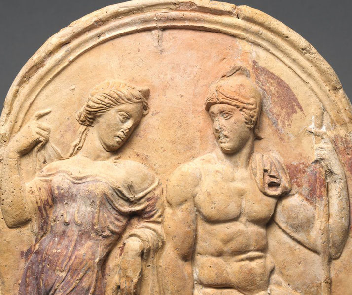 A terracotta relief depicts Aphrodite and Ares. The goddess gestures elegantly, while the armored god holds a spear. 