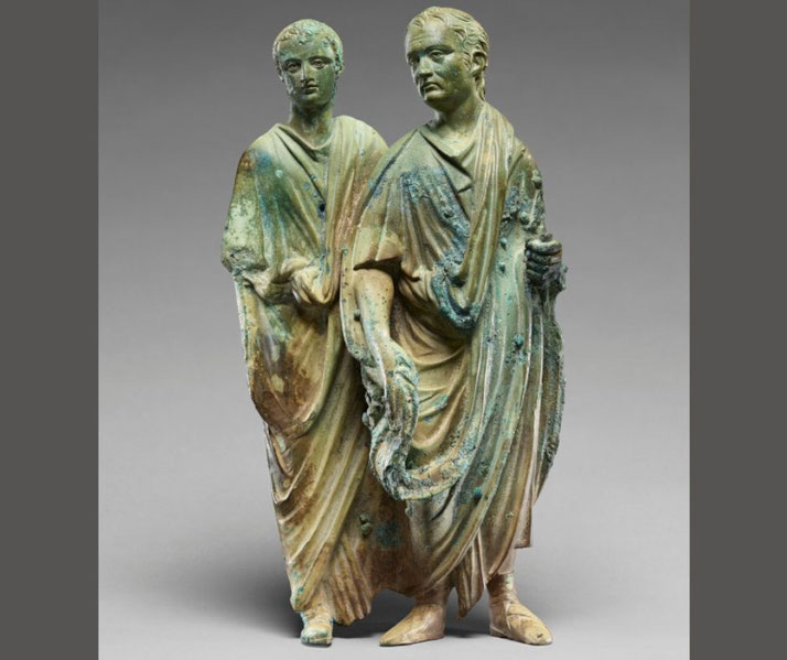 Roman marble relief showing two men in togas; one holds a scroll, suggesting scholarly or priestly status.