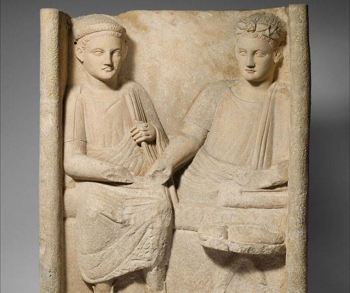 A limestone funerary stele depicts a banquet scene, showing two figures seated, possibly symbolizing status or the afterlife.