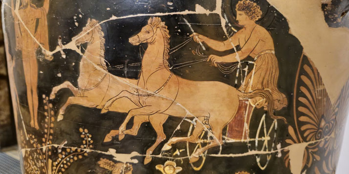 Ancient Greek vase painting shows a charioteer guiding two galloping horses, with flowing garments and intricate details on a dark background.