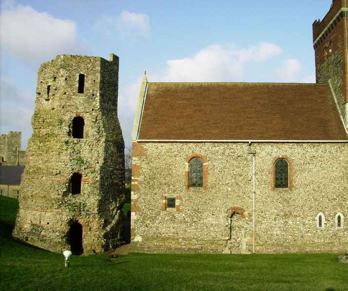 A crumbling stone tower beside a solid, stone church with arched windows.