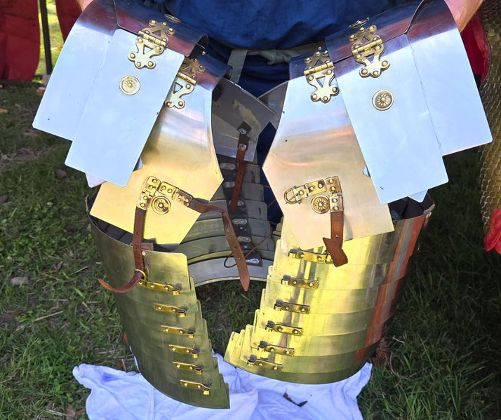 A Roman lorica segmentata, a segmented plate armor used by legionaries, is displayed with brass fittings and leather straps.