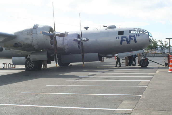 A restored B-29 Superfortress named “FIFI” is parked on display with people gathered beneath its nose section.