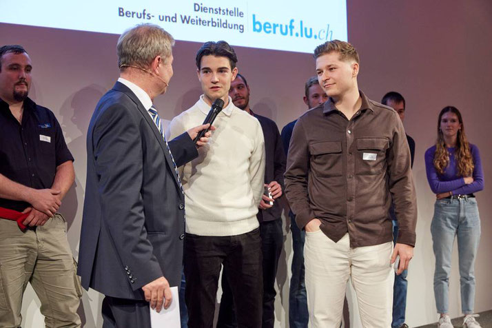  Marcel Schwerzmann interviewt die beiden Bronzemedaillengewinner in der Disziplin Entrepreneurship: Yannick Tschuor aus Adligenswil und Gian Wyss aus Zell