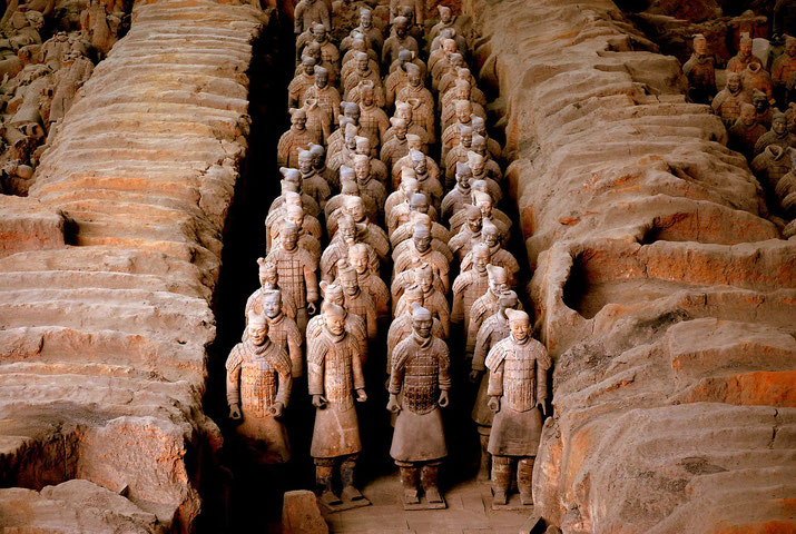 Rows of the Terracotta Army, a collection of life-sized statues of warriors and horses, buried to accompany China's first emperor, Qin Shi Huang, in his tomb, showcasing intricate detail and uniformity.