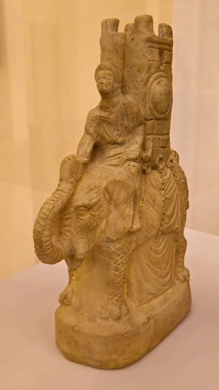Clay sculpture of an armored elephant with a tower on its back and a rider seated on top, likely depicting a war elephant from antiquity.