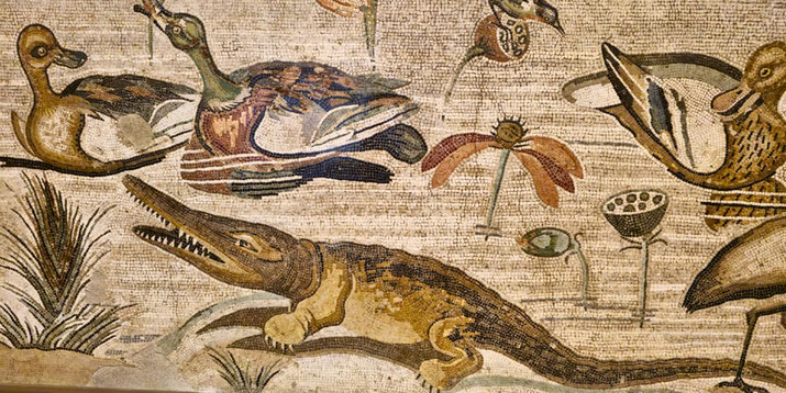 Ancient mosaic showing ducks and a crocodile among lotus flowers and reeds in a lively wetland scene.