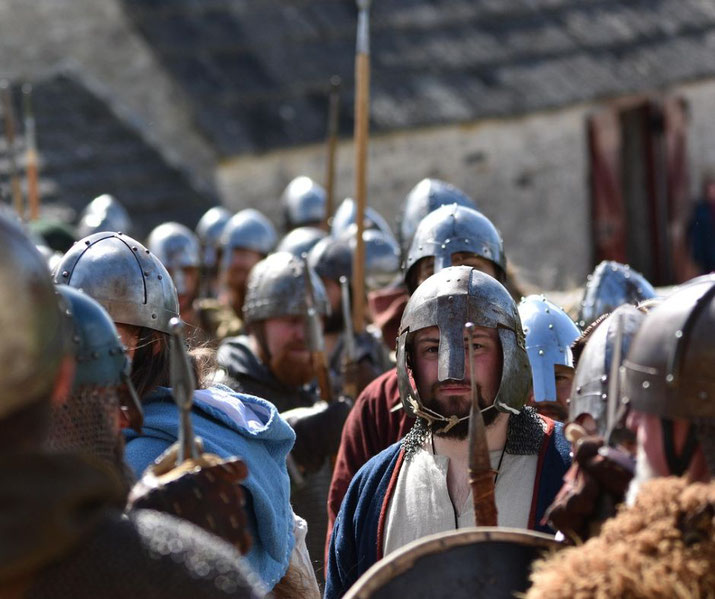  group of medieval soldiers wearing metal helmets and chainmail, carrying spears and shields.