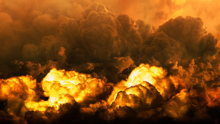 Dramatic fiery explosion with thick, dark smoke clouds rising and glowing intensely with orange and yellow flames.