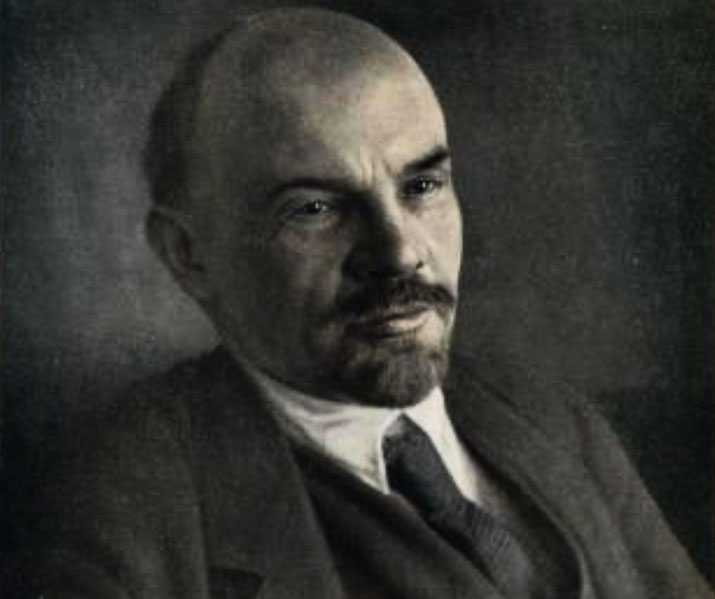 Sepia-toned portrait of a bald man with a goatee in a suit and tie, gazing slightly off-camera with a serious expression.
