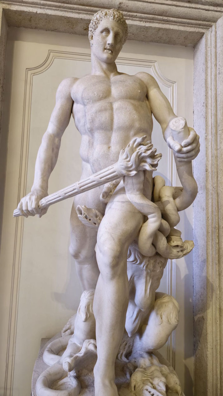 Marble statue of a muscular man battling a serpent-like creature with a torch, likely depicting Hercules fighting the Hydra in dramatic classical style.