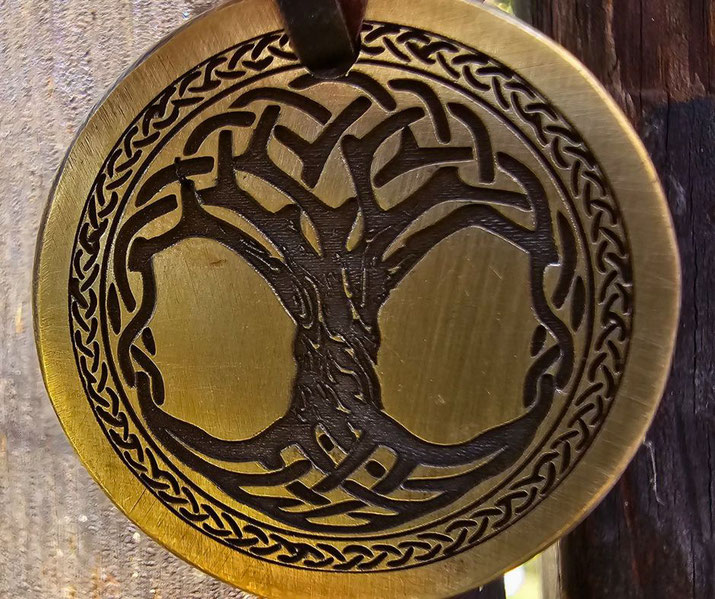 A round brass pendant with an intricate engraving of the Norse Yggdrasil, the Tree of Life.