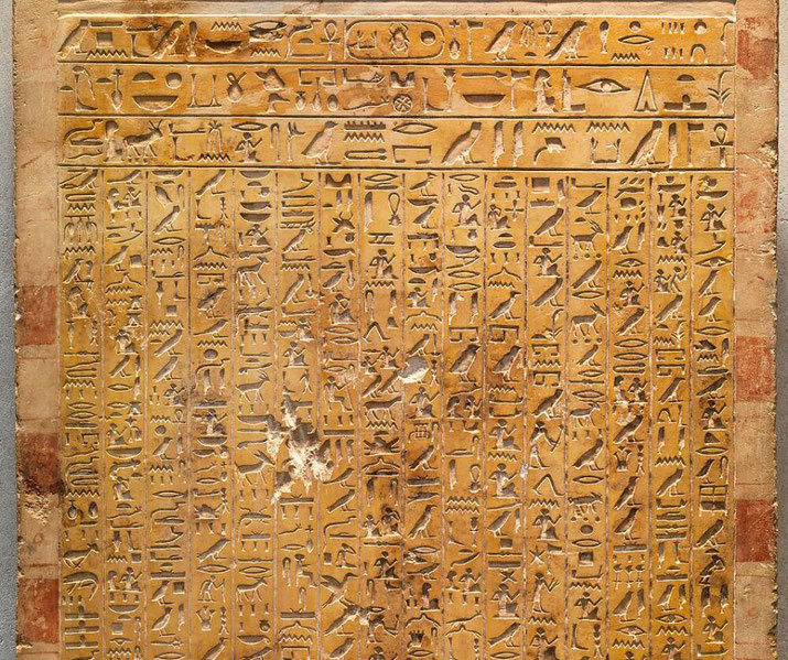 An ancient Egyptian stela with detailed hieroglyphic inscriptions carved into a golden limestone surface. The text is arranged in neat vertical columns, preserving historical and religious records.