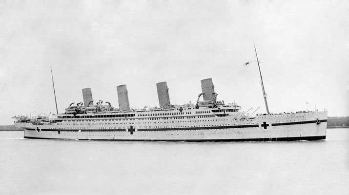 The RMS Britannic repurposed as a hospital ship during wartime, painted white with large red crosses and a stripe, featuring four smokestacks and calm waters in the background.