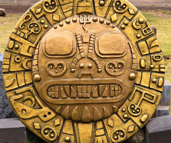 A large golden circular artifact with intricate carvings, possibly inspired by Incan or Mesoamerican motifs.