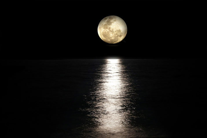 A full moon illuminating a dark sky, casting a bright, reflective light path across the surface of a calm ocean, creating a serene and tranquil nighttime scene.