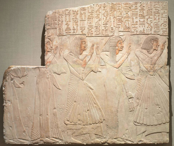 An ancient Egyptian tomb relief depicting the Chief Physician Amenhotep and his family. The figures wear pleated garments, raise their hands in reverence, and are accompanied by hieroglyphs.