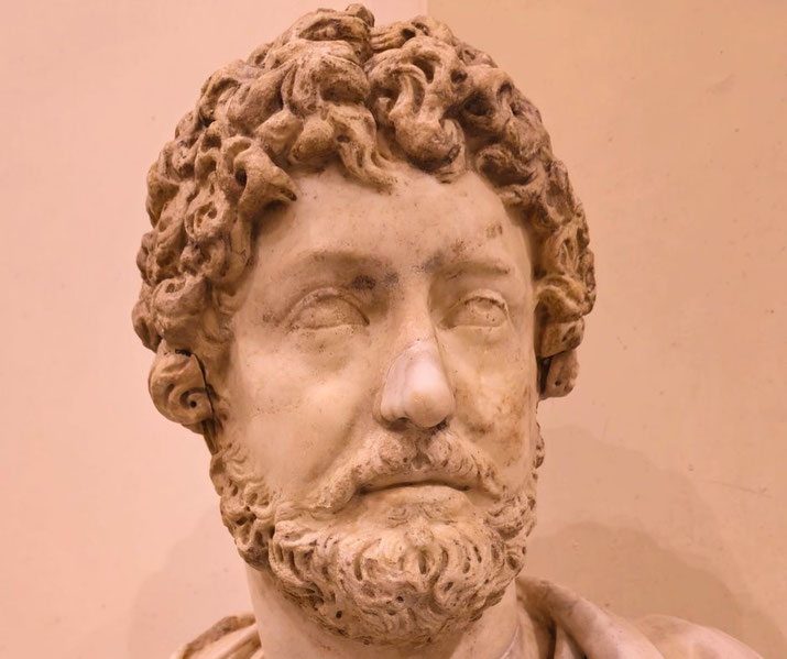 A marble bust of Marcus Aurelius, the Roman emperor and Stoic philosopher. His curly hair and beard are finely detailed, though the nose appears damaged.