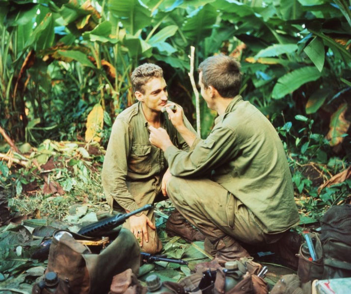 Two soldiers in banana trees apply camouflage paint during the Vietnam War, 12 September 1968.