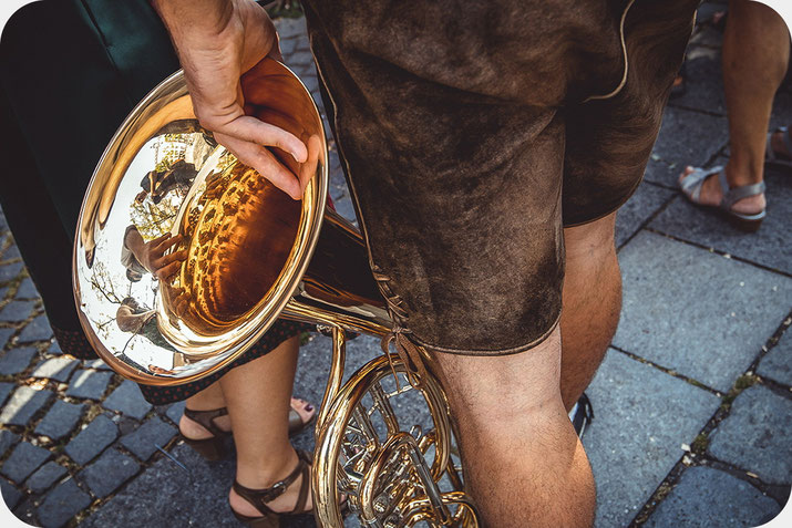  Detailaufnahme aus Bayern mit traditioneller Lederhose und Tuba in dokumentarischer Reisefotografie