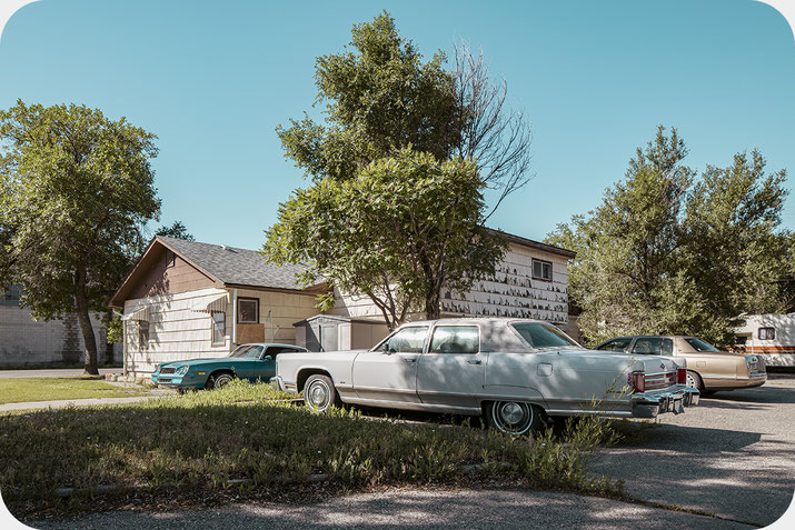 Atmosphärische Reisefotografie alter Autos vor einem Haus in Montana mit zeitloser Stimmung
