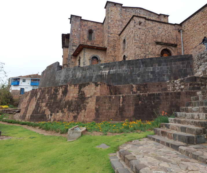 A historic site featuring Inca stone walls with precise masonry at the base and a colonial-era church built on top.