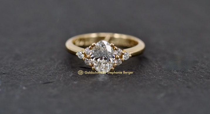 Trilogie-Verlobungsring mit ovalem Diamanten und je drei seitlichen Brillanten, handgefertigt vom Goldschmied in 750er Gold.