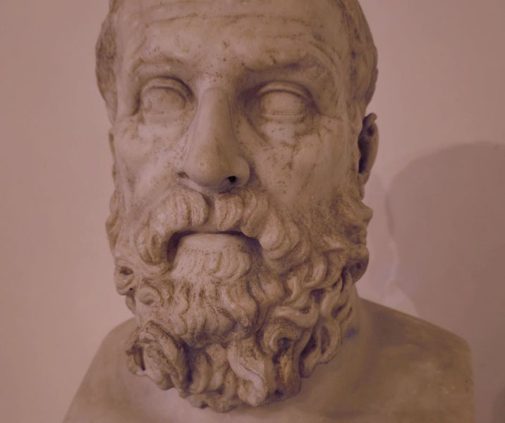 Marble bust of a bearded man with curly hair and a solemn expression, featuring deeply carved facial details and blank, introspective eyes.