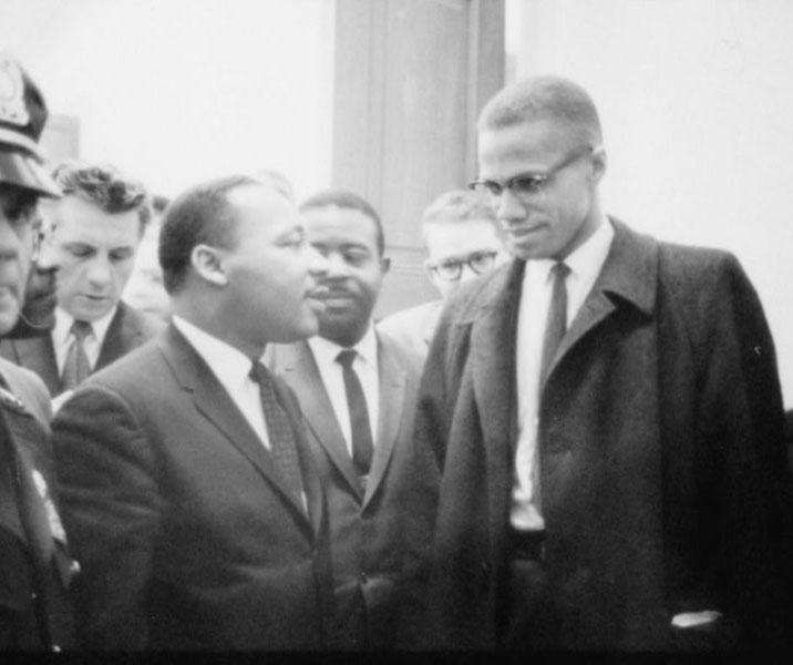 A moment between two well-dressed men in conversation, surrounded by others.