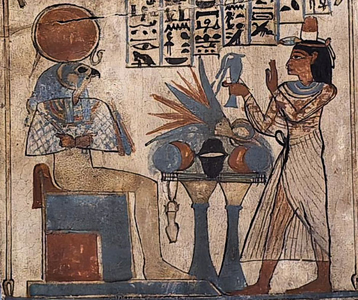 Ancient Egyptian wall painting shows a figure offering to a seated falcon-headed deity adorned with a sun disk and hieroglyphs above.