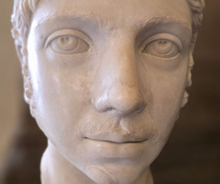 Marble bust of a young man with sharp features, short hair, and faint facial hair, showcasing a calm, focused expression and realistic detailing.