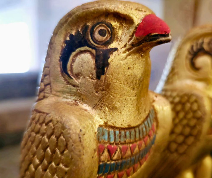 Close-up of a golden falcon statue with painted details, representing an ancient Egyptian symbol or deity.