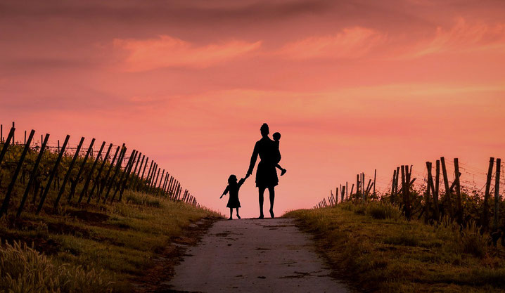 Mother walking with children on path at sunset