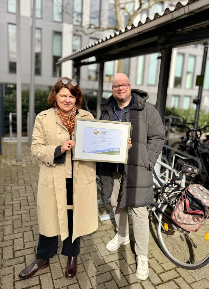 Birgit Kind und Theo Peters von der TARGOBANK präsentieren stolz das Gold-Siegel als "Fahrradfreundlicher Arbeitgeber" in Duisburg. Foto: TARGOBANK AG