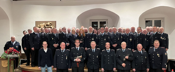 Viele Menschen in dunkelblauen Uniformen der Freiwilligen Feuerwehr posieren für ein Gruppenfoto.