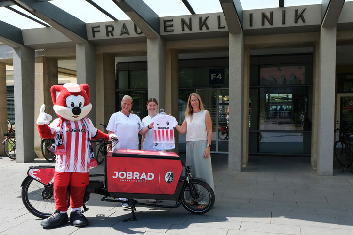 ©JobRad: JobRad-Gesellschafterin Sandra Prediger schenkt Neuankömmlingen des Universitätsklinikums Freiburg SC-Trikots (Saison 2025/26). Begleitet vom "Füchsle", PD Dr. Mirjam Kunze (Ärztliche Leiterin Geburtshilfe) und Carolina Fink (Leitende Hebamme)