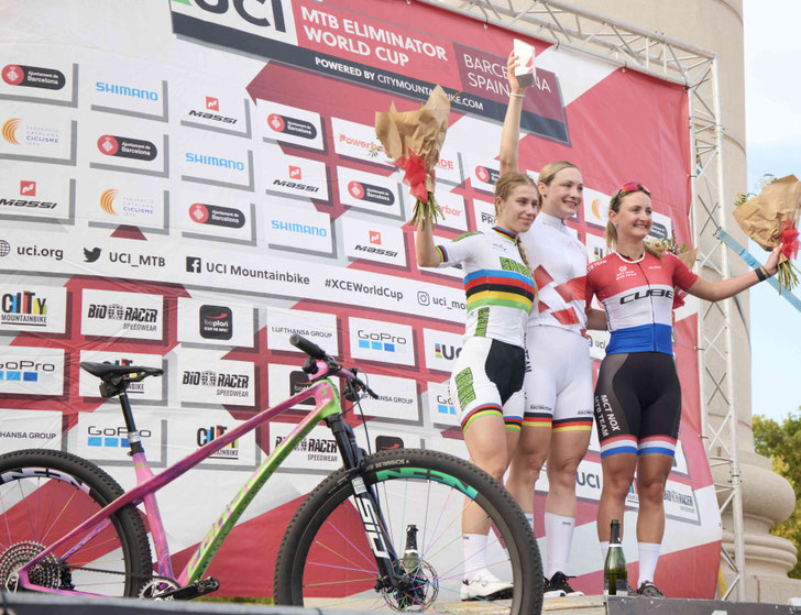 corratec Racingteam Fahrerin Marion Fromberger (Mitte) krönt ihr Jahr mit dem Gesamtsieg im UCI Mountainbike Eliminator Worldcup 2025. Im Vordergrund das Erfolgsrad: corratec Revo Bow SL Factory© corratec